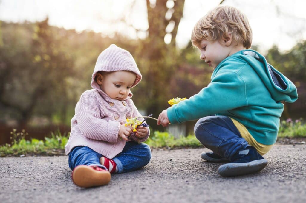 A toddler boy and girl outside on a spring walk.